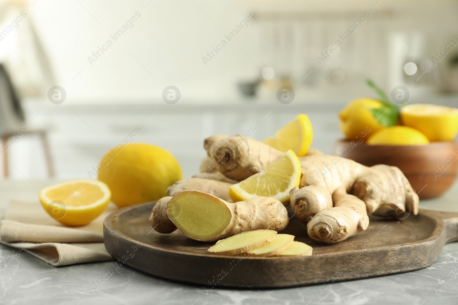 Photo of Fresh lemons and ginger on grey marble table indoors