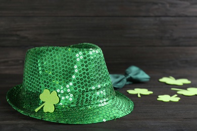 Photo of Leprechaun's hat and decorative clover leaves on black wooden background. St. Patrick's day celebration