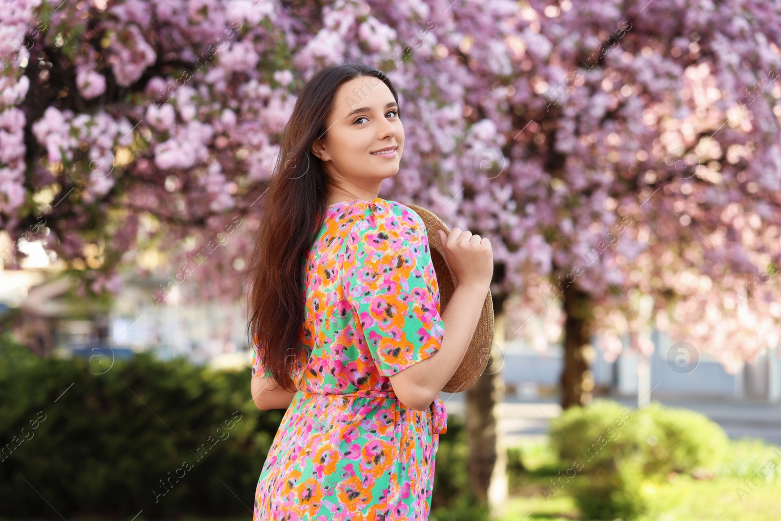 Photo of Beautiful woman with straw hat near blossoming tree on spring day