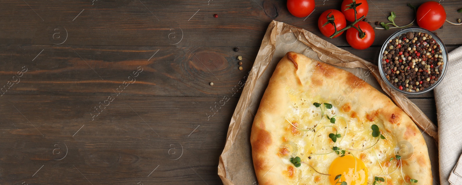 Image of Delicious Adjarian khachapuri served on wooden table, flat lay. Banner design with space for text