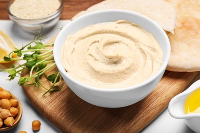 Delicious hummus and different ingredients on white table