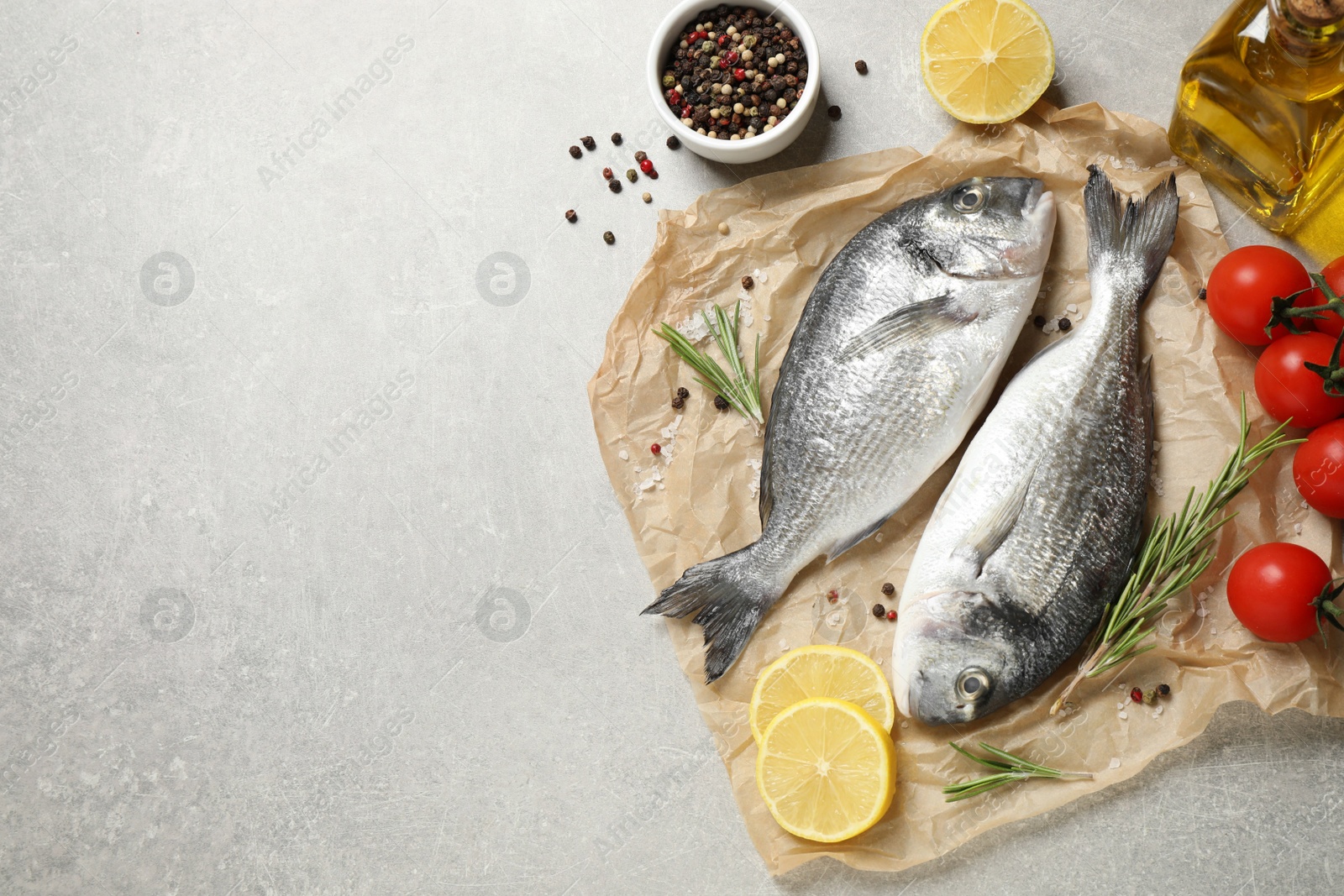 Photo of Flat lay composition with raw dorada fish on light grey table, space for text