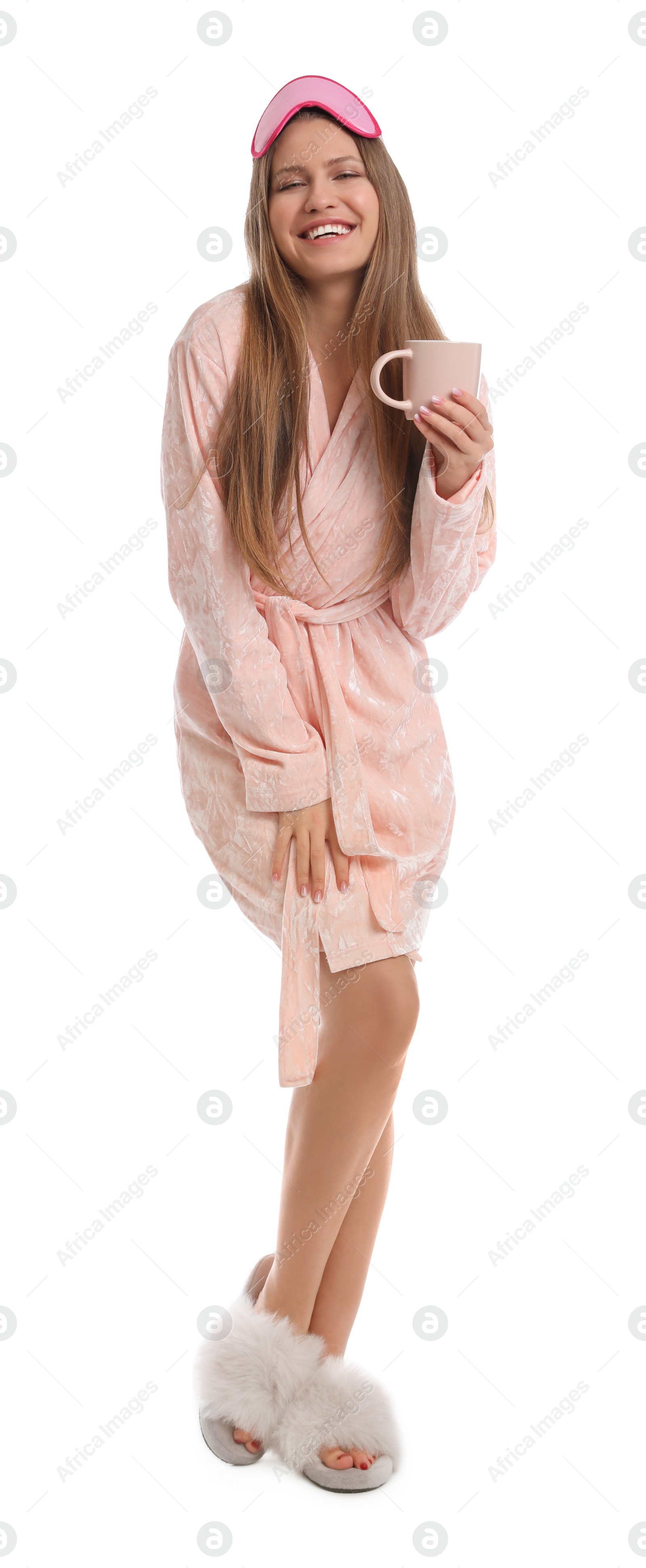 Photo of Young woman in bathrobe with sleep mask and cup of beverage on white background