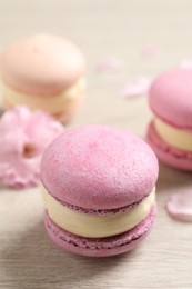 Pink macarons and flowers on white wooden table
