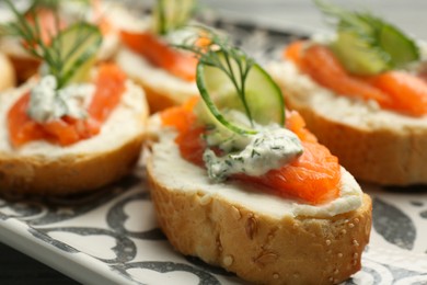 Photo of Tasty canapes with salmon, cucumber, cream cheese and dill on table, closeup