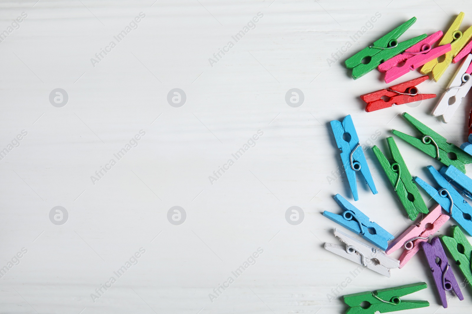 Photo of Many colorful clothespins on white wooden table, flat lay. Space for text