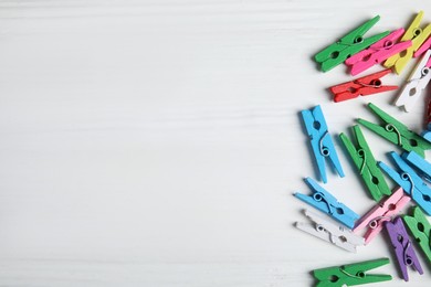 Photo of Many colorful clothespins on white wooden table, flat lay. Space for text