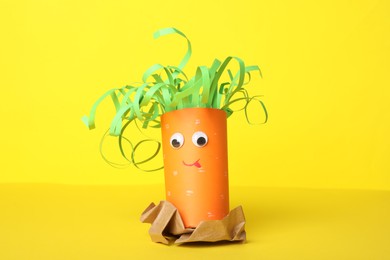 Photo of Toy carrot made of toilet paper hub on yellow background