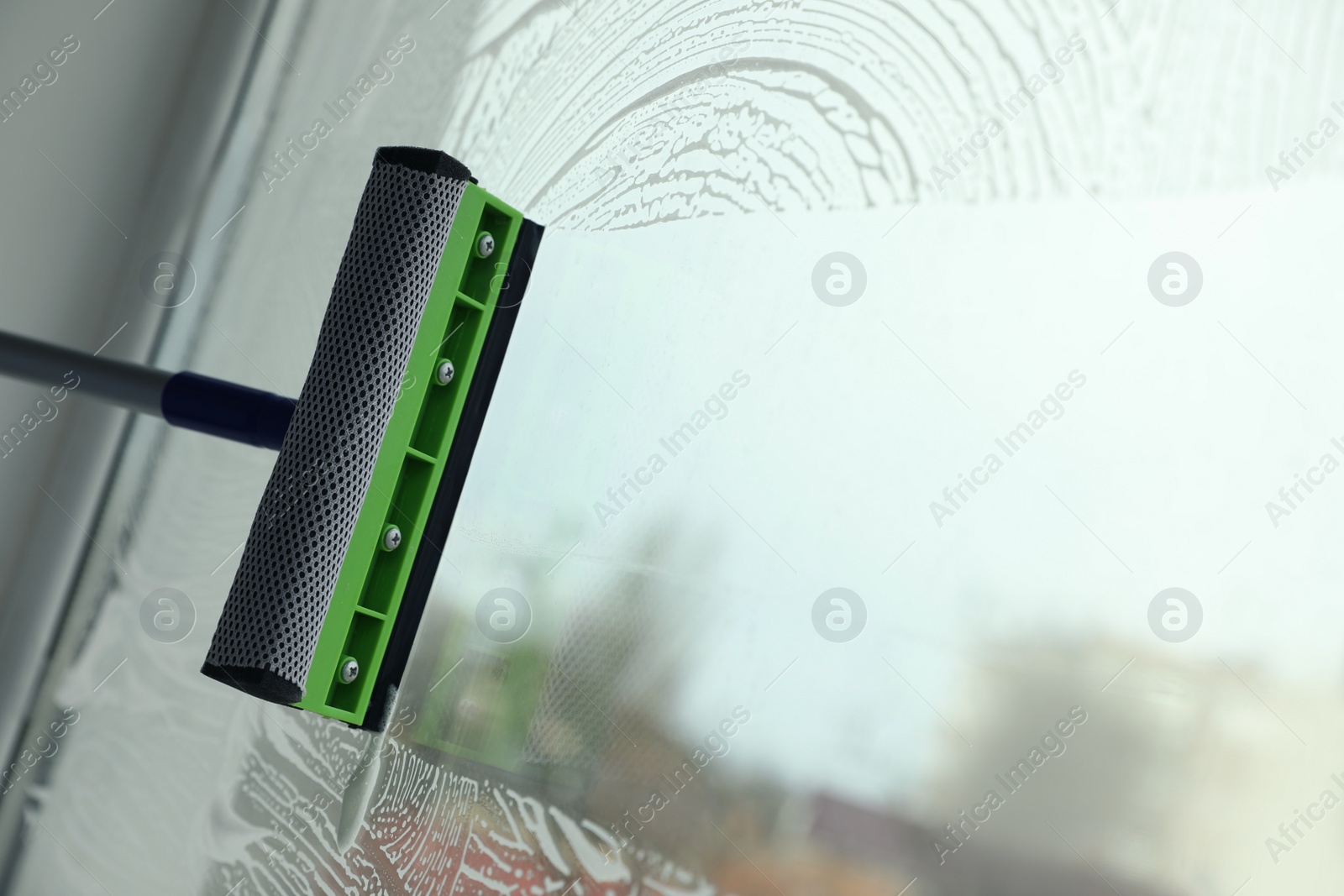 Photo of Cleaning window with squeegee indoors. Space for text