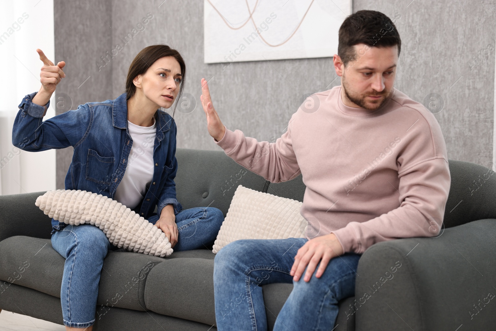 Photo of Tired husband stopping his wife indoors. Relationship problems