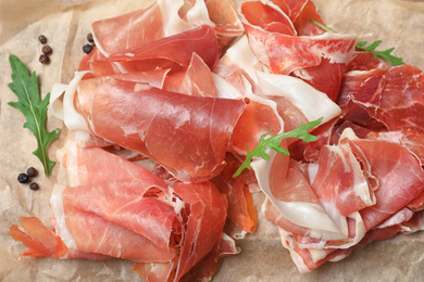 Photo of Pile of tasty prosciutto on parchment, closeup