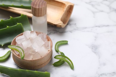 Photo of Aloe vera gel, bottle and slices of plant on white marble table, closeup. Space for text