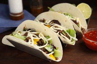 Photo of Delicious tacos with fried meat and cheese on wooden table, closeup