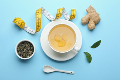 Photo of Flat lay composition with cup of diet herbal tea and measuring tape on light blue background