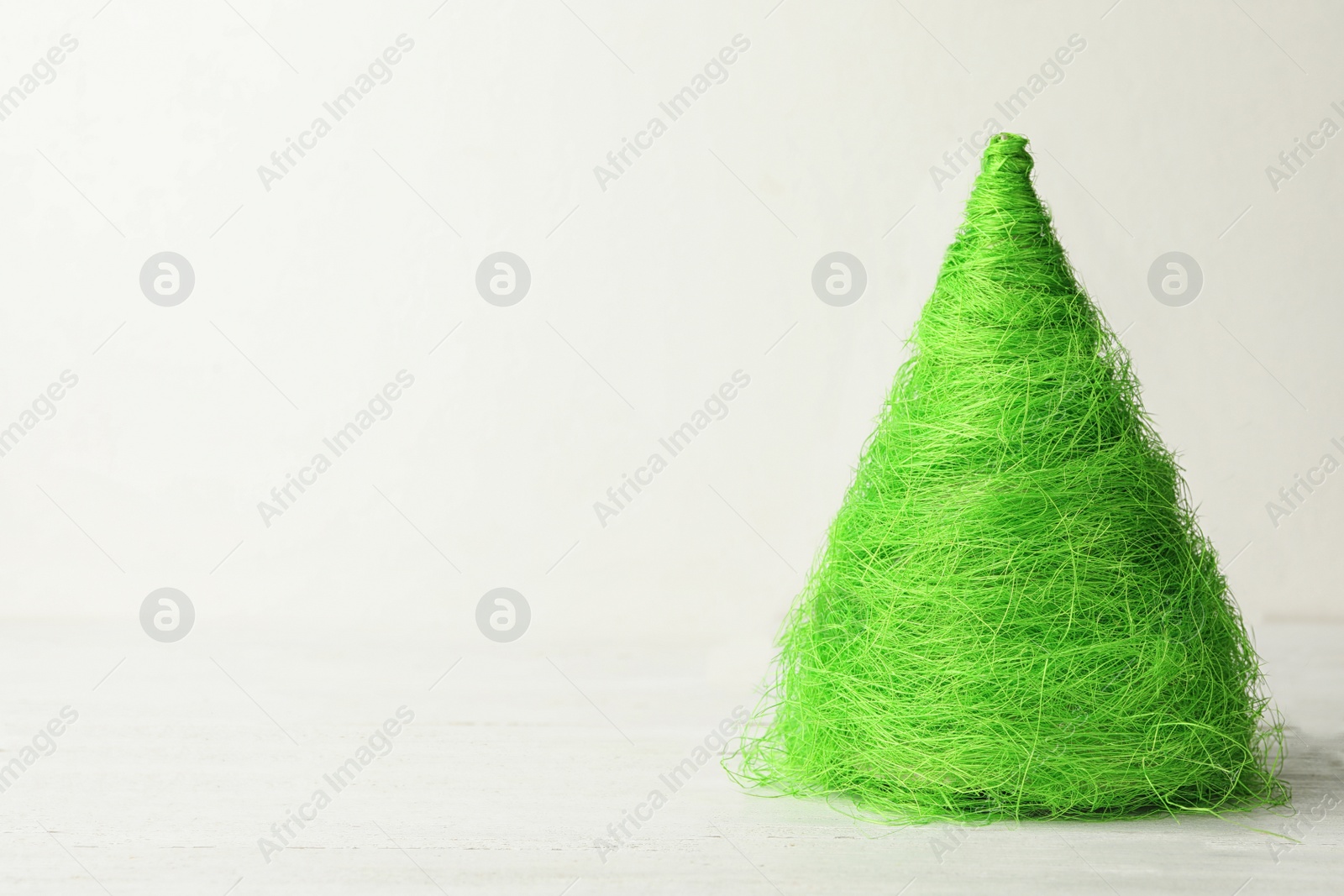 Photo of Christmas tree made of green threads on table against white background, space for text