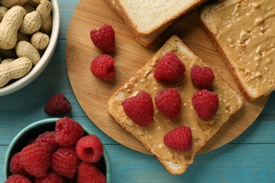 Photo of Delicious toasts with peanut butter, raspberries and nuts on light blue wooden table, flat lay