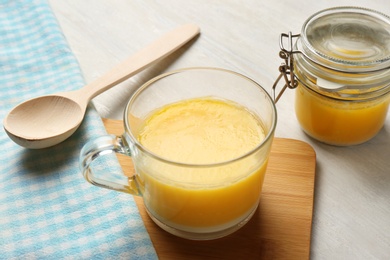 Glass cup and jar with clarified butter on table