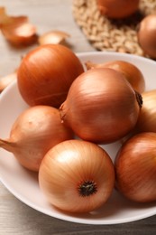 Photo of Many ripe onions on wooden table, closeup