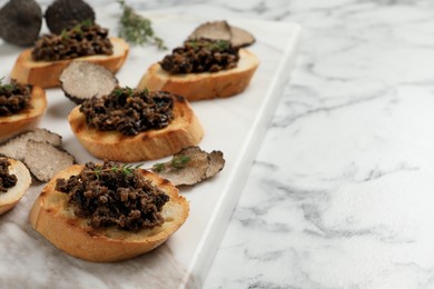 Delicious bruschettas with truffle sauce and thyme on white marble table. Space for text