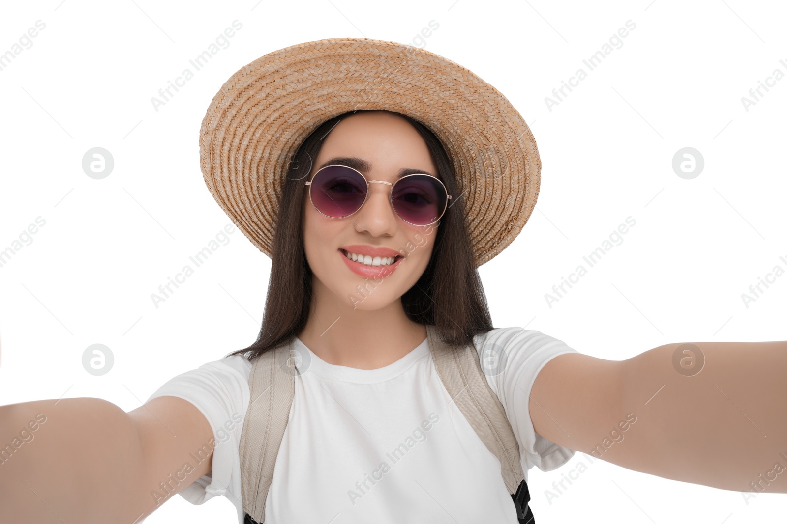 Photo of Smiling young woman in sunglasses and straw hat taking selfie on white background