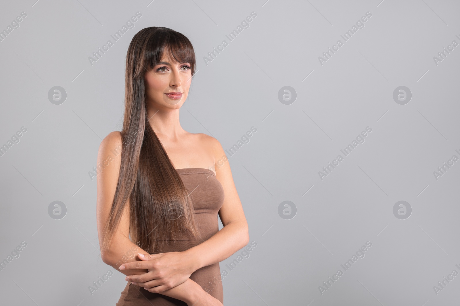 Photo of Hair styling. Beautiful woman with straight long hair on grey background, space for text