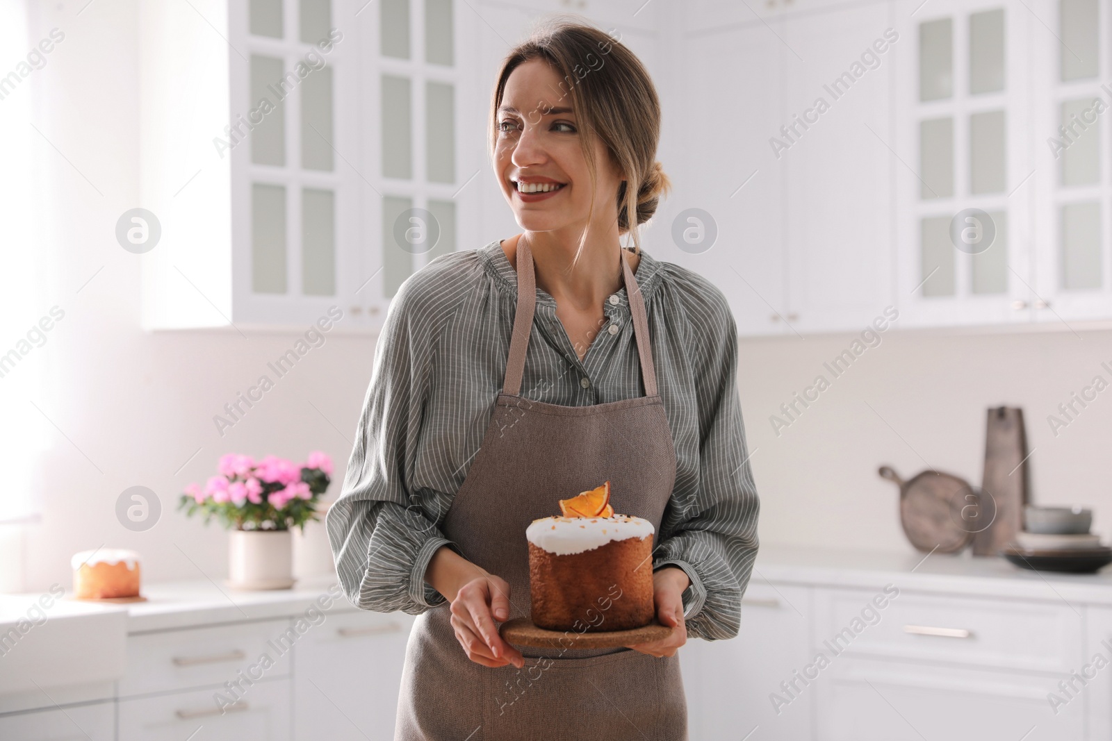 Photo of Young woman with traditional decorated Easter cake in kitchen