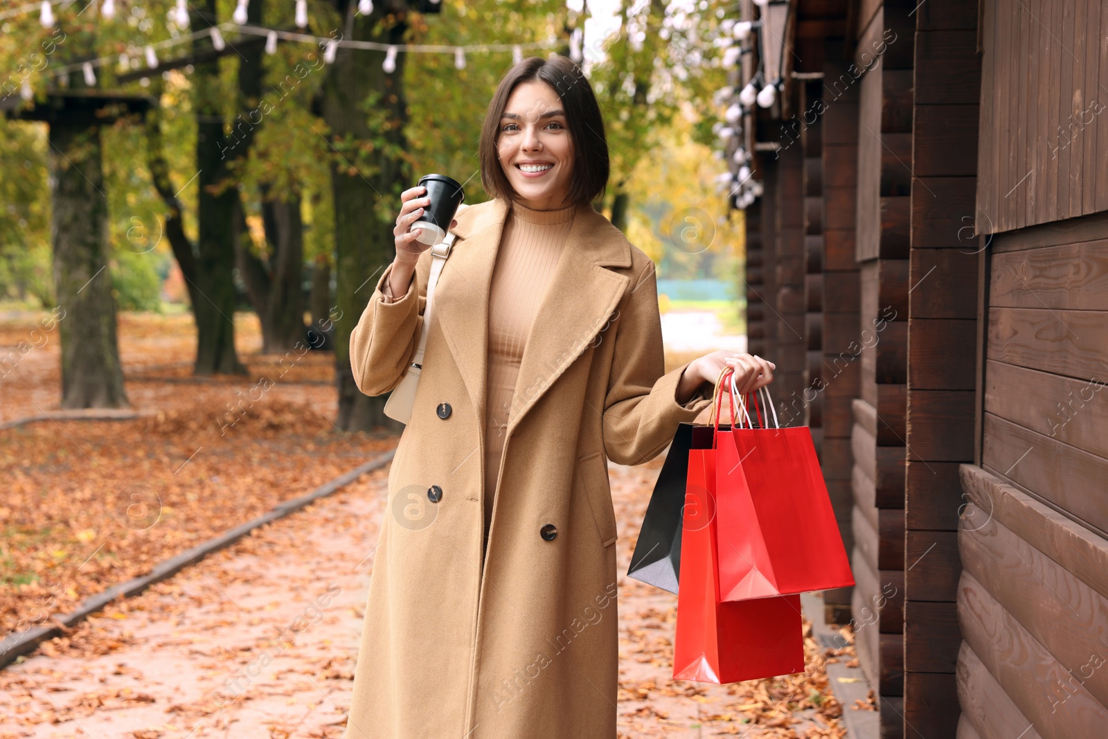 Photo of Special Promotion. Happy young woman with shopping bags and cup of drink on city street