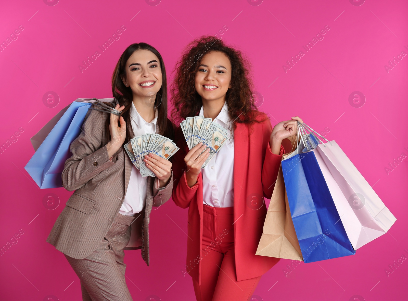 Photo of Young women with money and shopping bags on color background