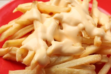 Photo of Delicious french fries with cheese sauce on plate, closeup