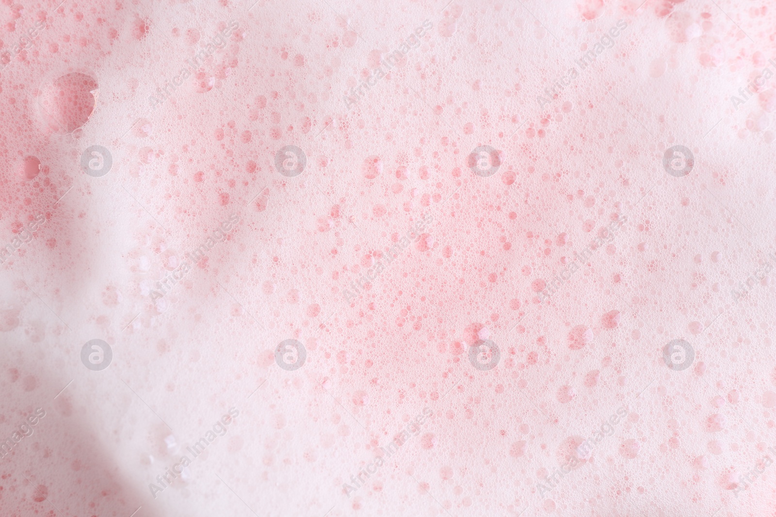 Photo of White fluffy foam on pink background, top view