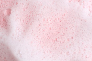 Photo of White fluffy foam on pink background, top view