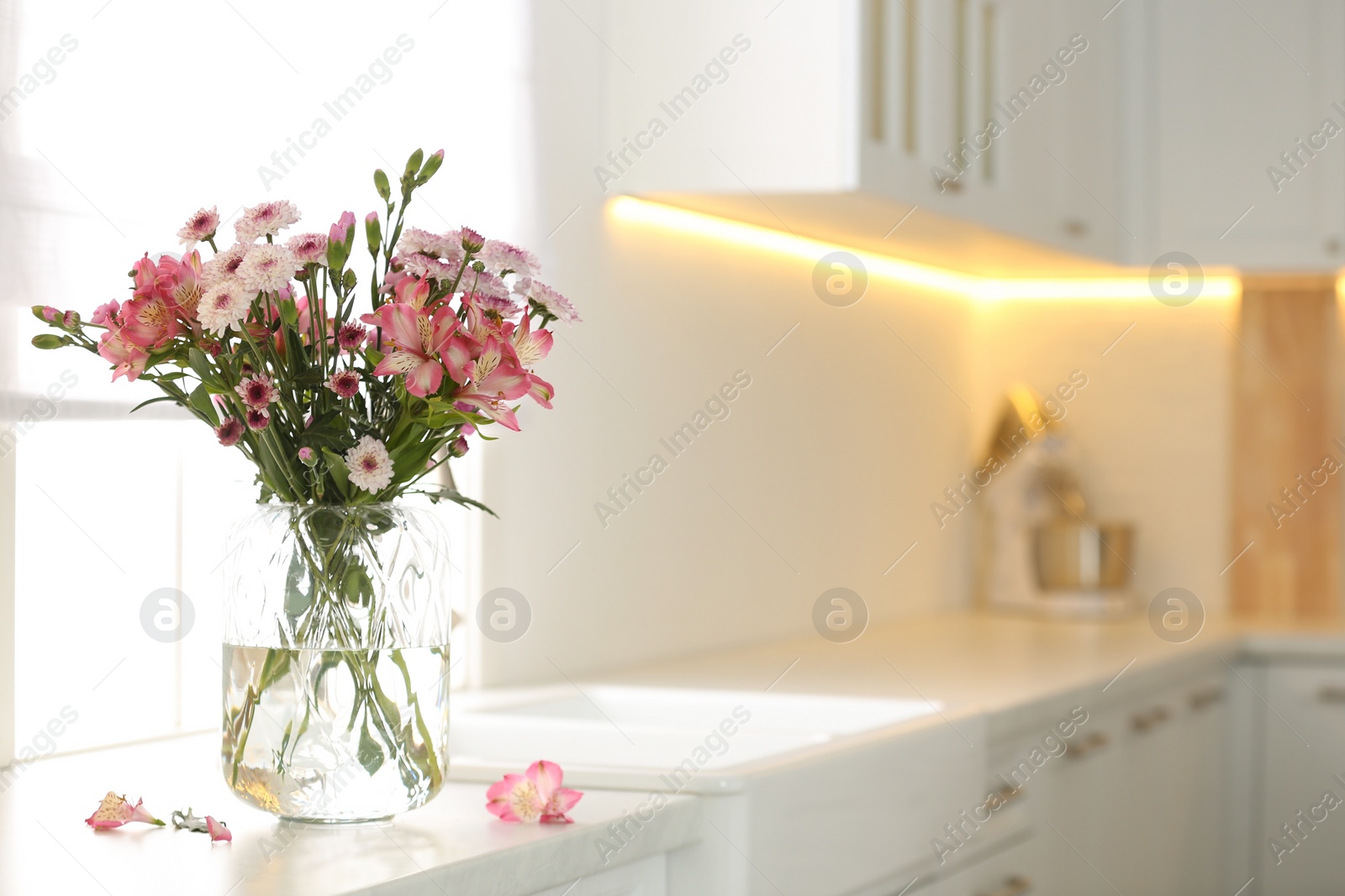 Photo of Vase with beautiful flowers on kitchen counter, space for text. Stylish element of interior design