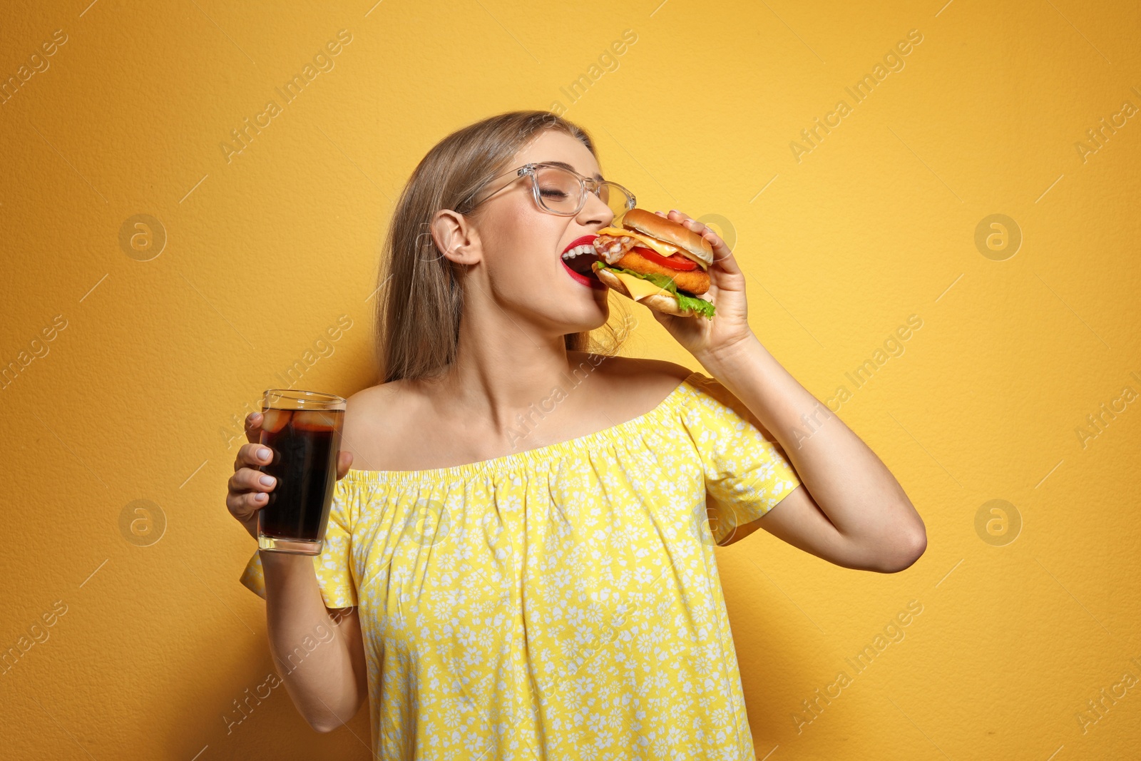 Photo of Pretty woman with tasty burger and cola on color background