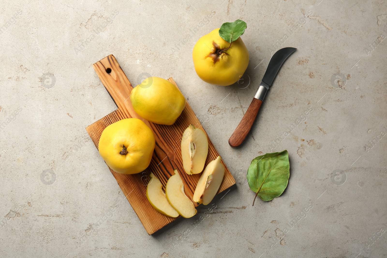 Photo of Tasty ripe quince fruits and knife on grey table, flat lay