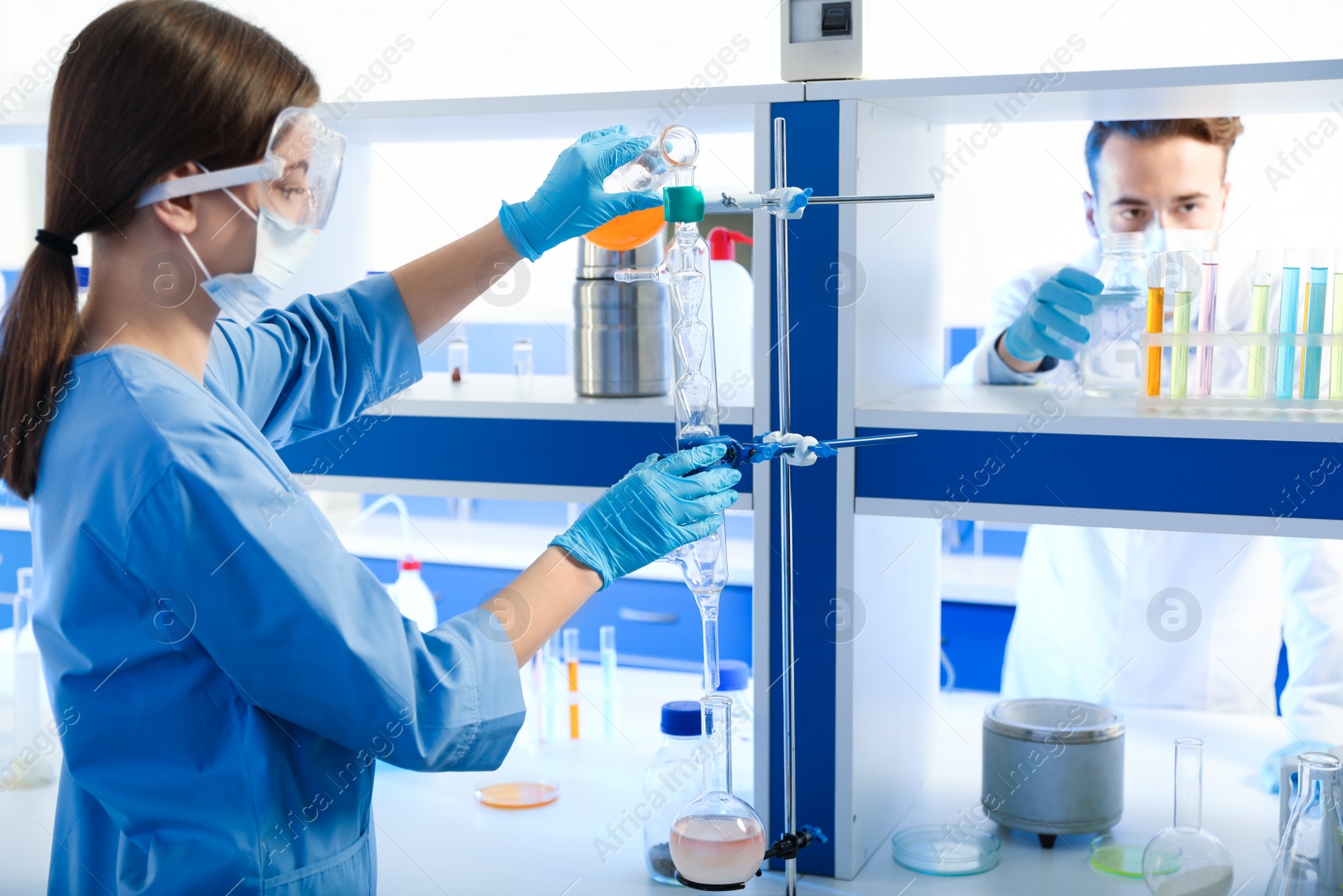 Photo of Scientist pouring liquid through glass distillation condenser indoors. Laboratory analysis