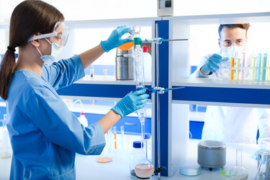 Scientist pouring liquid through glass distillation condenser indoors. Laboratory analysis