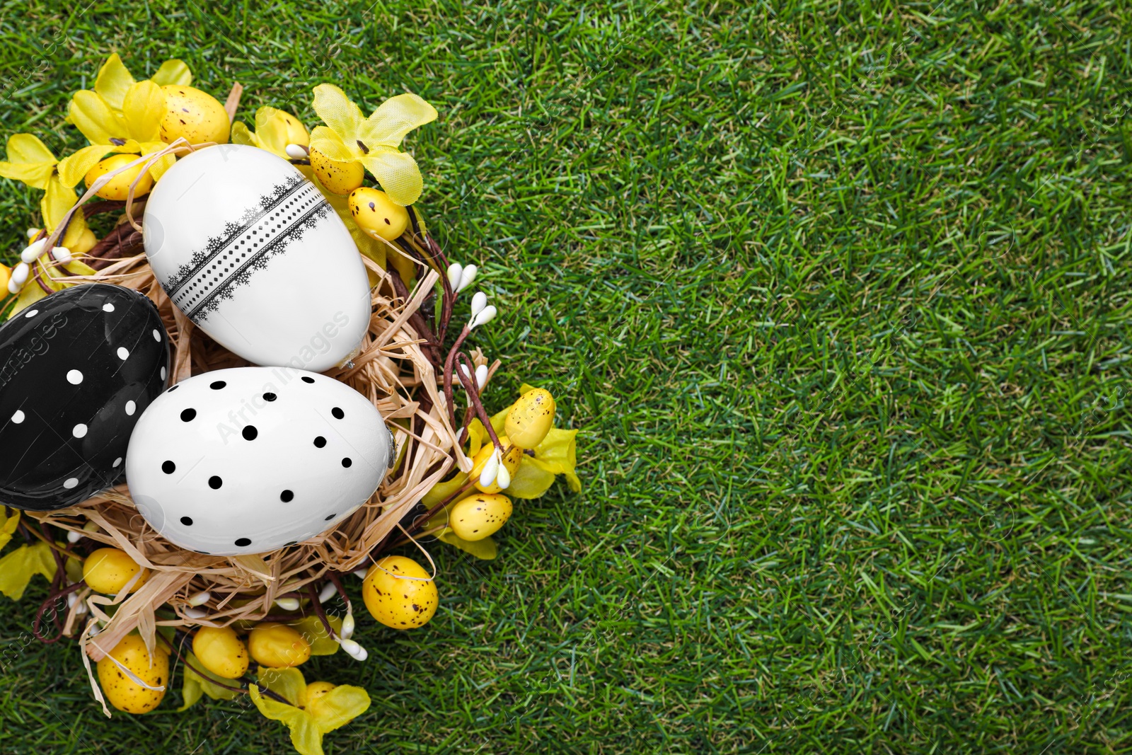 Photo of Festively decorated Easter eggs on green grass, top view. Space for text