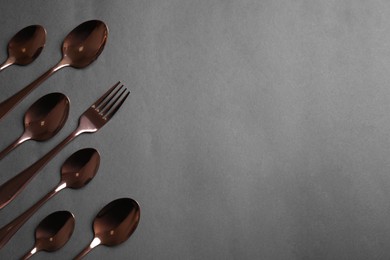 Spoons and fork on grey background, flat lay. Space for text