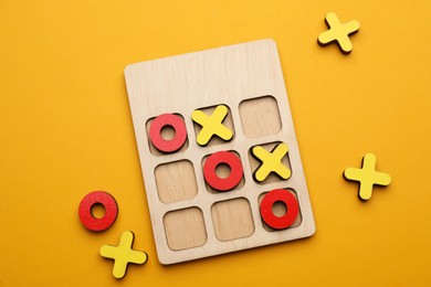 Photo of Tic tac toe set on yellow background, flat lay