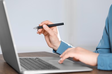 Photo of Woman with pen working on laptop, closeup. Electronic document management