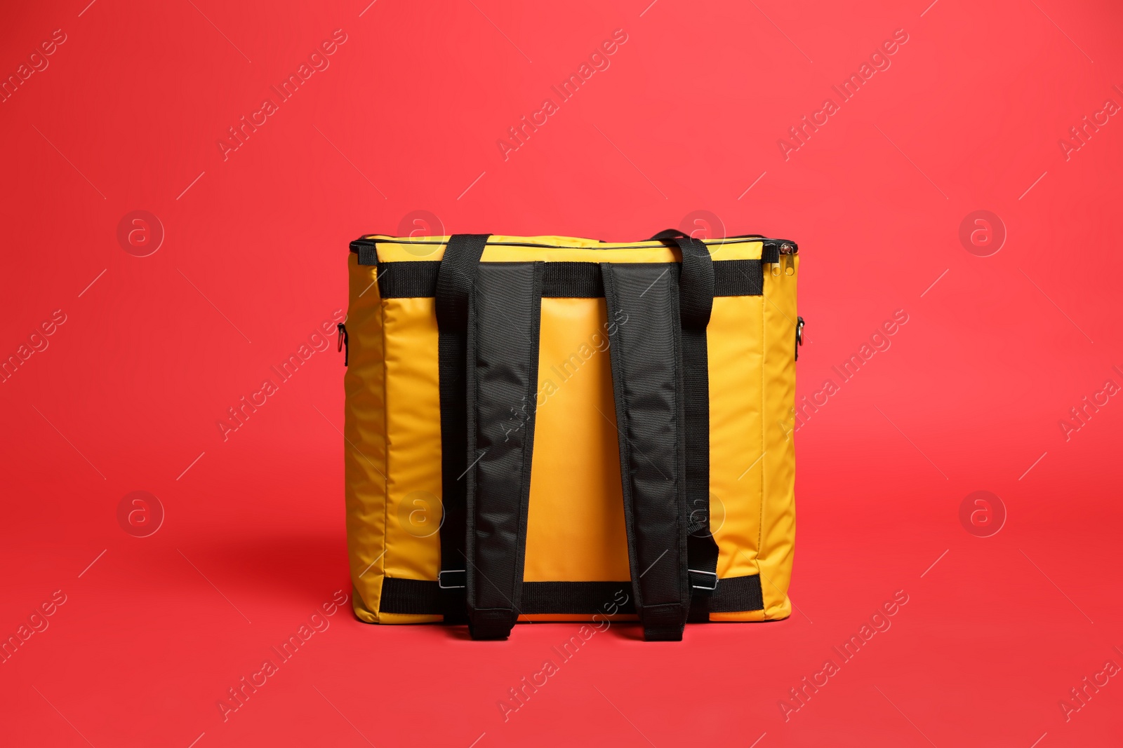 Photo of Modern yellow thermo bag on red background