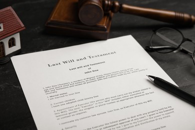 Photo of Last will and testament near house model, glasses, gavel on black table, closeup