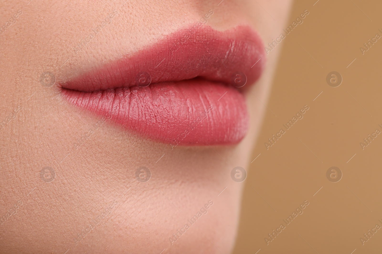 Photo of Young woman with beautiful full lips on beige background, closeup