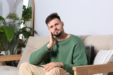 Photo of Young man suffering from ear pain at home