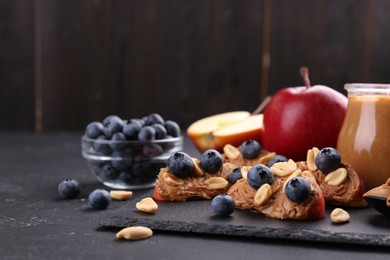 Fresh apples with peanut butter and blueberries on dark table