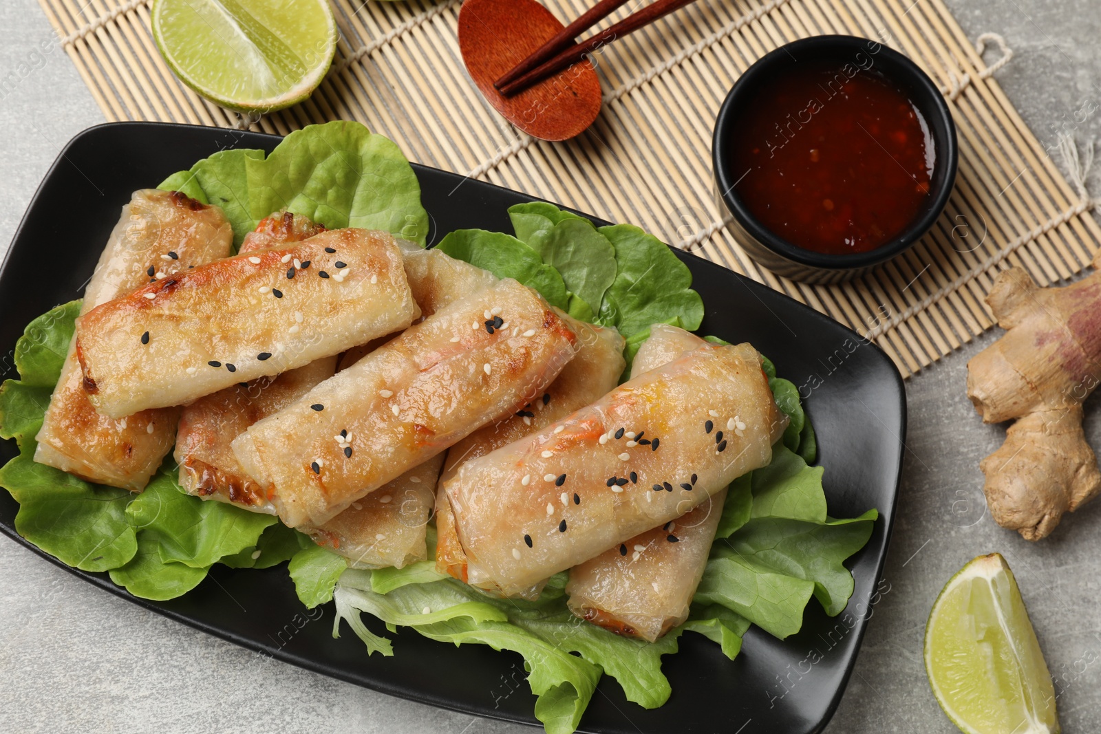 Photo of Tasty fried spring rolls served on gray table, flat lay