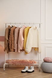 Photo of Rack with stylish warm clothes and shoes in modern dressing room