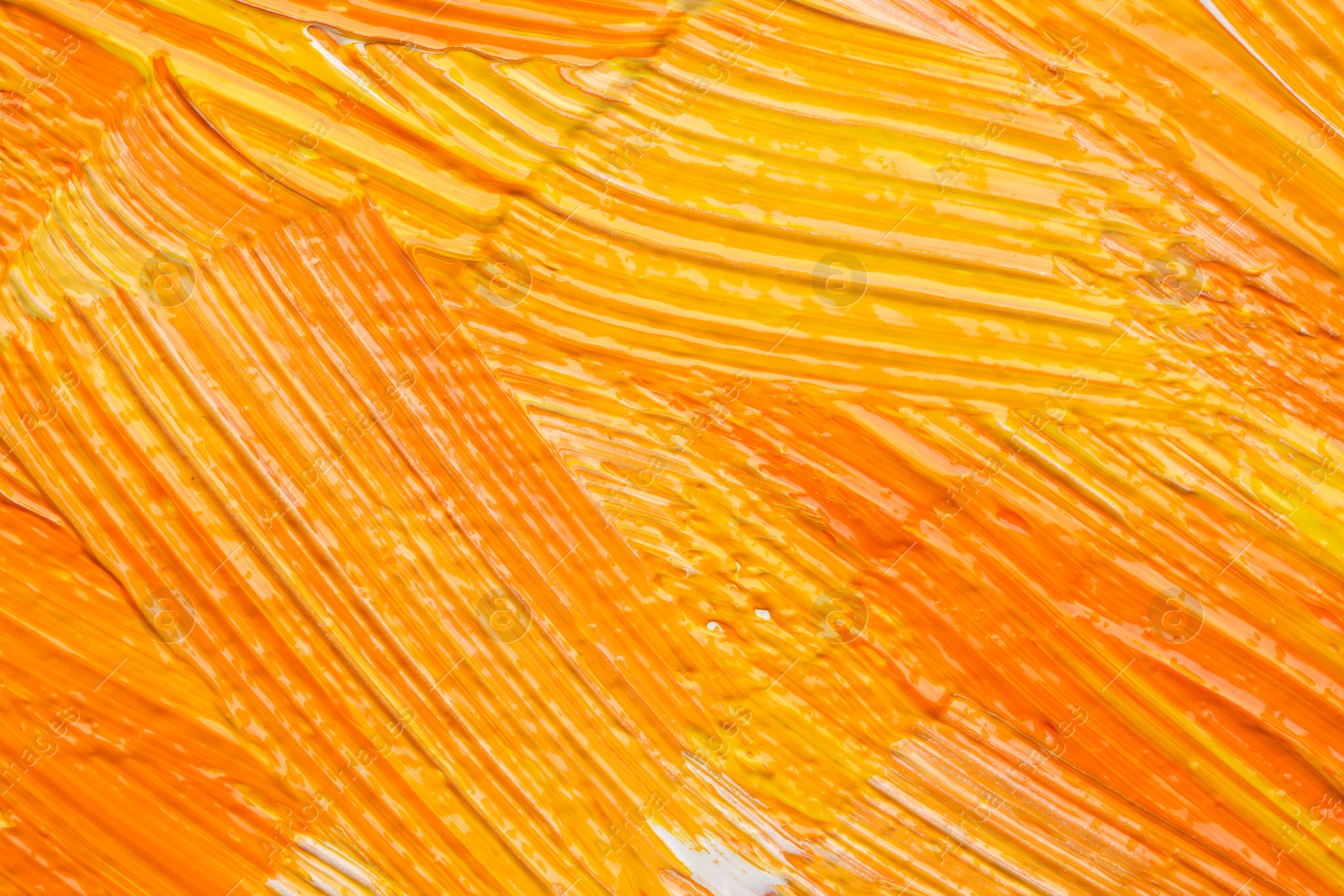 Photo of Beautiful strokes of yellow and orange oil paints as background, closeup