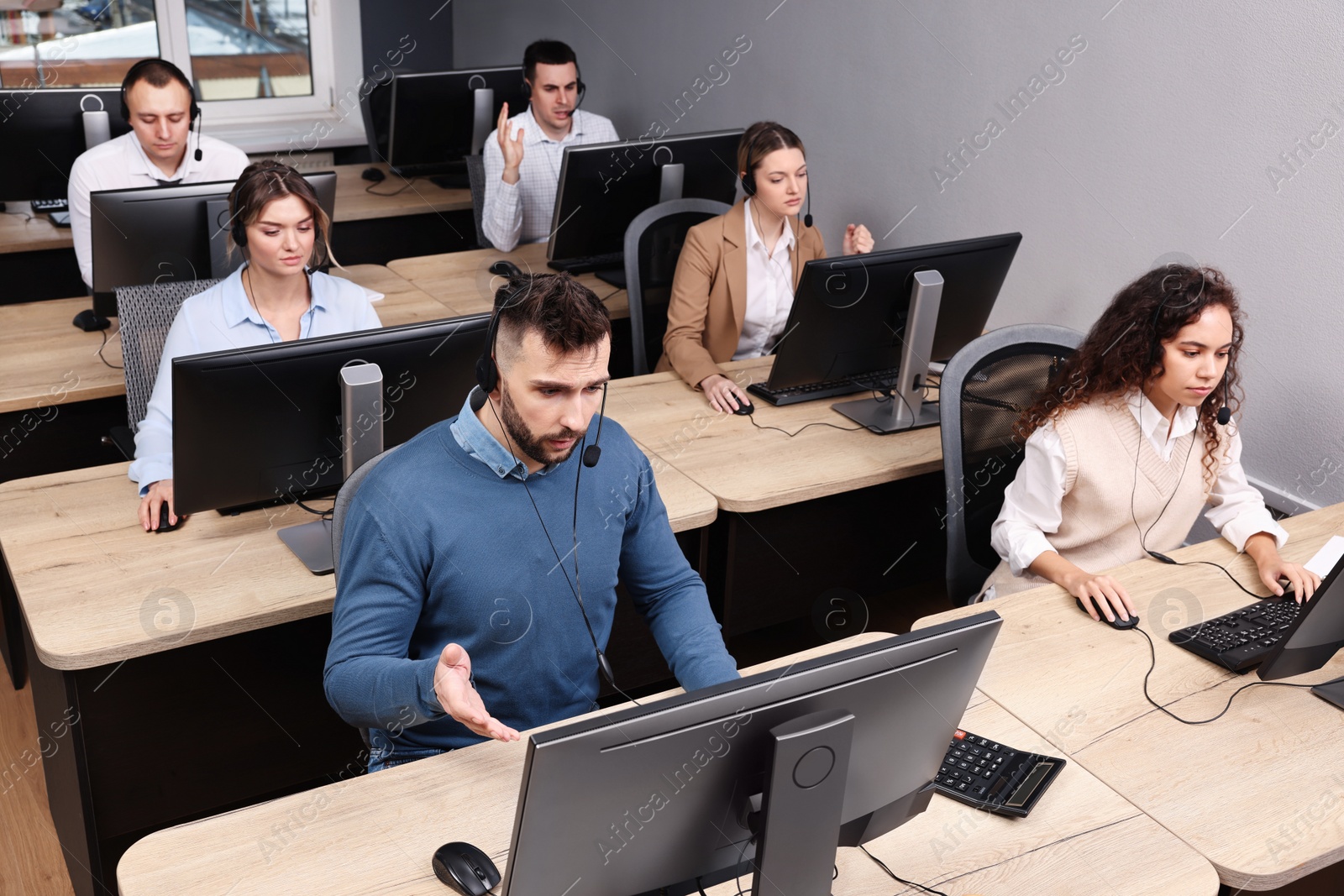 Photo of Call center operators with headsets working in modern office, above view