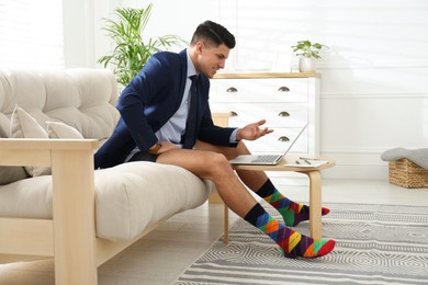 Photo of Businessman in jacket and underwear having videocall on laptop at home